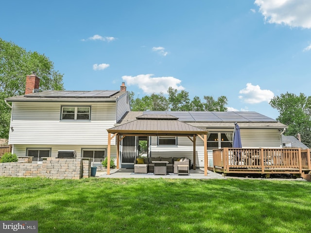 back of house featuring outdoor lounge area, a yard, and roof mounted solar panels