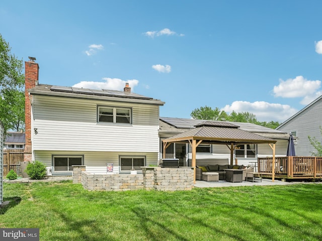 back of property featuring an outdoor hangout area, solar panels, a gazebo, a lawn, and a chimney