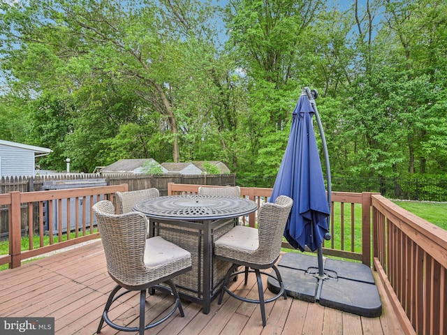 wooden terrace with a fenced backyard, outdoor dining area, and view of wooded area