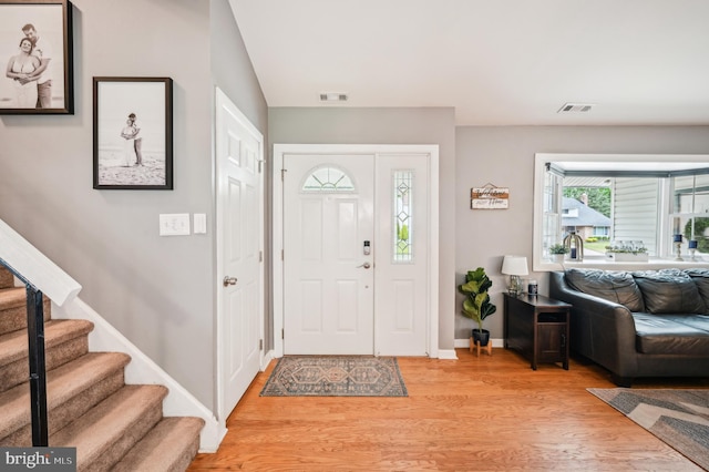 entryway with light wood finished floors, baseboards, and stairway