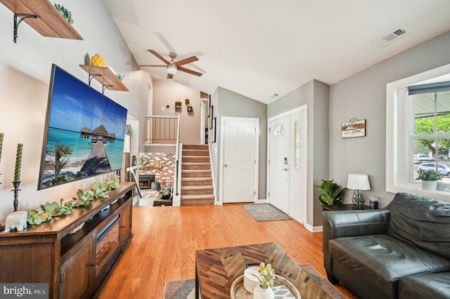 living room with light wood-style floors, vaulted ceiling, stairway, and a ceiling fan