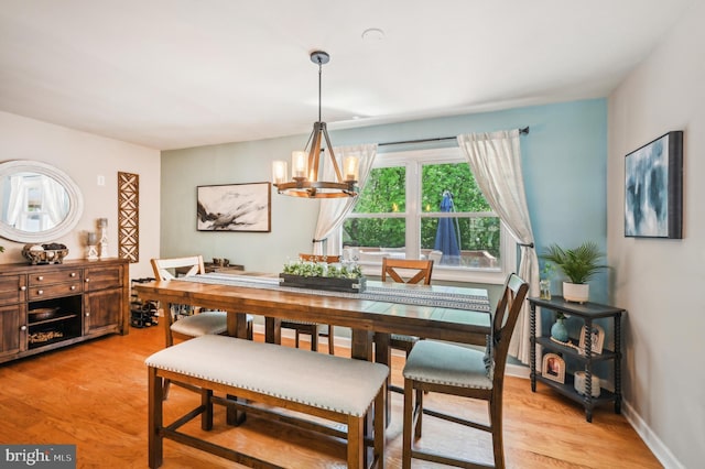 dining room featuring a chandelier, light wood-type flooring, and baseboards