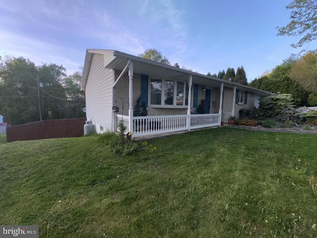 ranch-style house featuring covered porch and a front yard