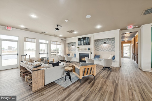 living room featuring visible vents, a glass covered fireplace, and wood finished floors