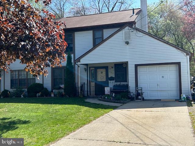 traditional-style home with a porch, a chimney, a front yard, a garage, and concrete driveway