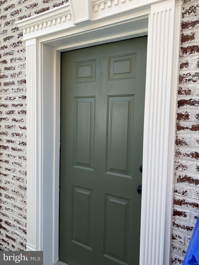 doorway to property featuring brick siding