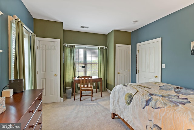 bedroom with baseboards, visible vents, and light carpet
