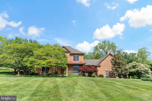 view of front of home with a chimney, brick siding, and a front yard