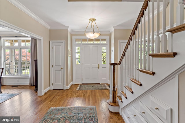 entryway with light wood-style floors, baseboards, ornamental molding, and stairs
