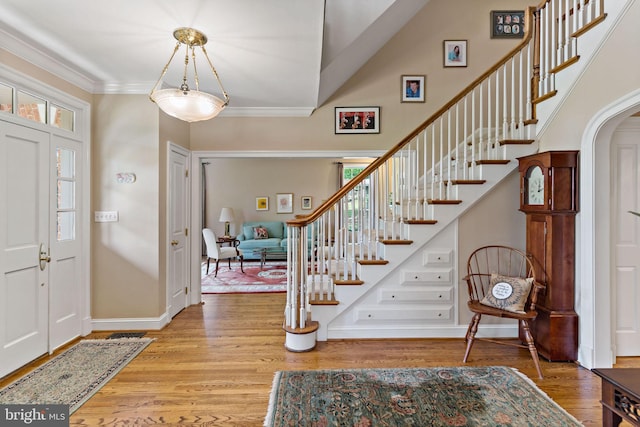 entrance foyer featuring stairway, arched walkways, baseboards, and wood finished floors