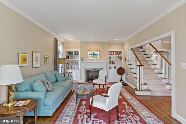 living area featuring crown molding, wood finished floors, stairway, and a fireplace