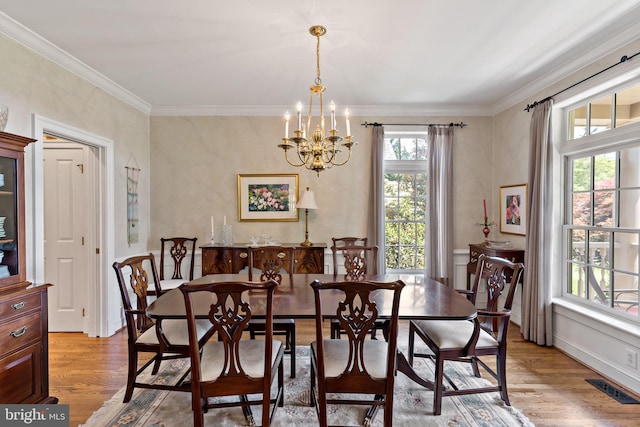 dining space with a chandelier, ornamental molding, wood finished floors, and visible vents
