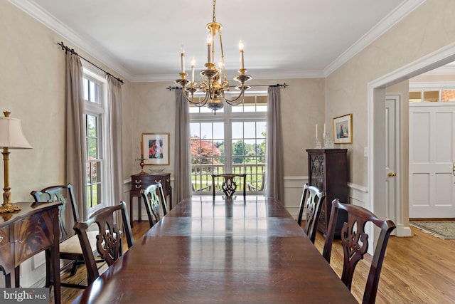 dining room with crown molding, an inviting chandelier, wood finished floors, and a decorative wall