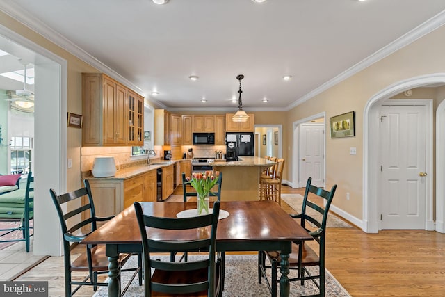 dining space featuring crown molding, baseboards, recessed lighting, arched walkways, and light wood-style flooring