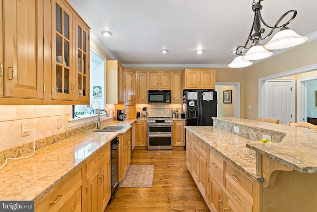 kitchen with light stone countertops, a sink, light wood-style floors, a kitchen island, and black appliances