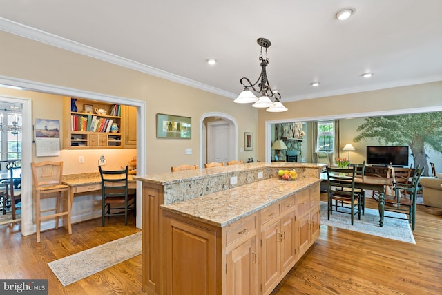 kitchen featuring crown molding, arched walkways, a center island, and light wood-type flooring