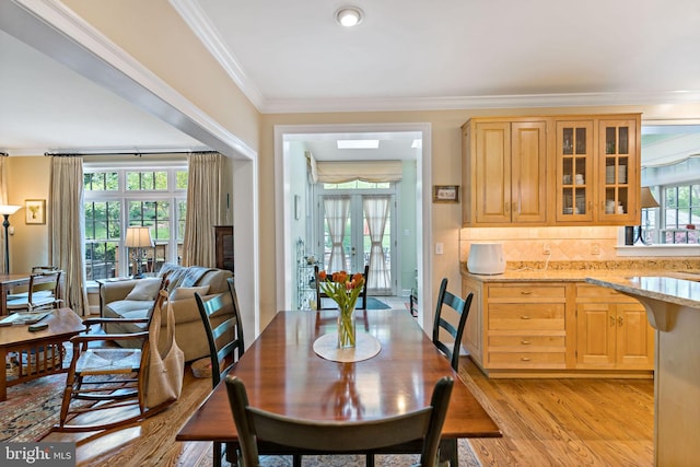 dining room with ornamental molding and light wood-style flooring