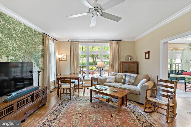 living room with ornamental molding, a ceiling fan, wallpapered walls, and wood finished floors