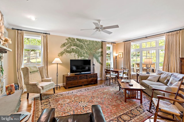 living room featuring crown molding, a ceiling fan, baseboards, and wood finished floors