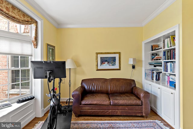 sitting room with light wood-type flooring, ornamental molding, and a wealth of natural light
