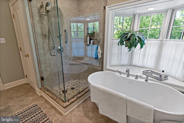 bathroom with tile patterned flooring, baseboards, a freestanding bath, and a stall shower