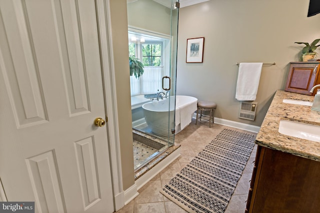 bathroom with double vanity, baseboards, tile patterned floors, a soaking tub, and a sink