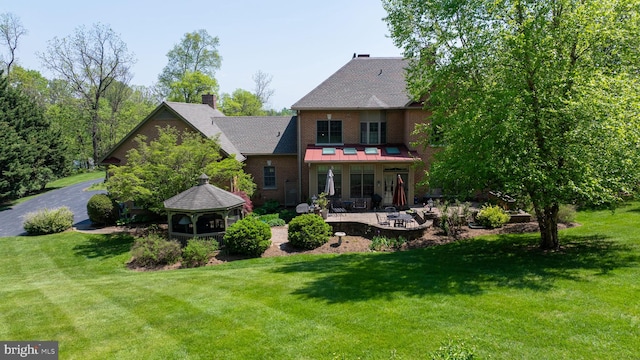 back of house featuring a gazebo, a lawn, a patio area, and a chimney