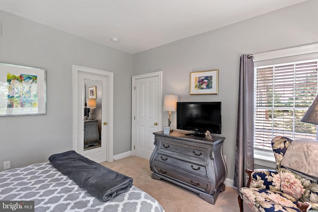 bedroom with light colored carpet and baseboards