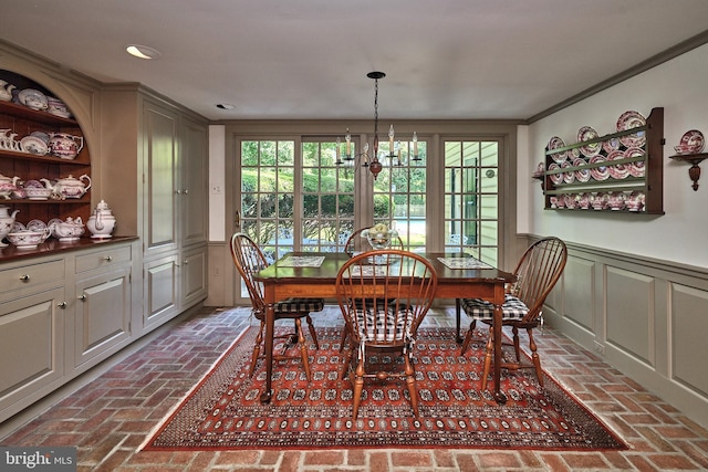 dining area with brick floors, recessed lighting, a chandelier, a decorative wall, and wainscoting