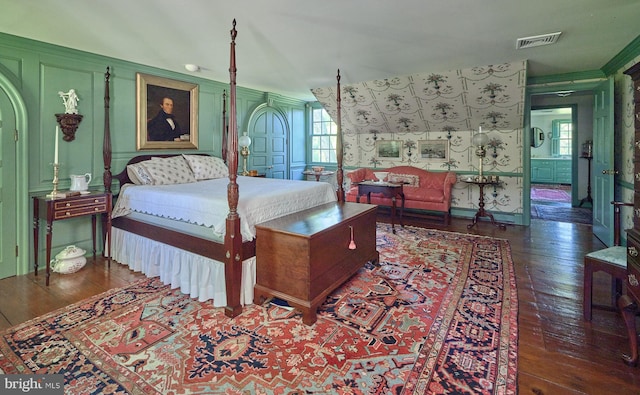 bedroom featuring a decorative wall, hardwood / wood-style flooring, multiple windows, and ornamental molding
