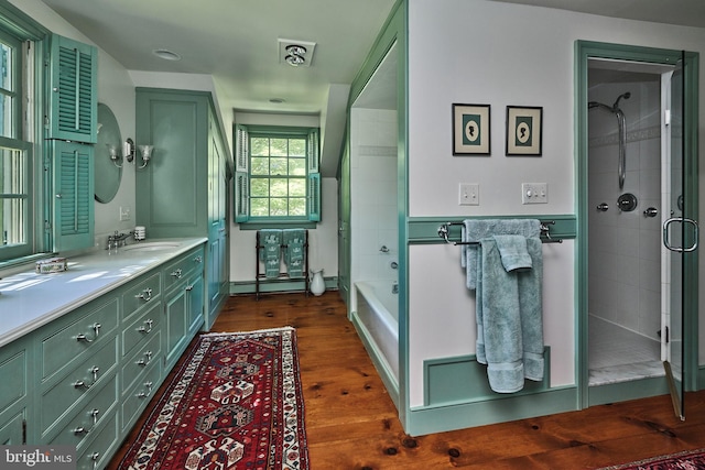 full bath with a tile shower, wood finished floors, vanity, a wainscoted wall, and a bathtub