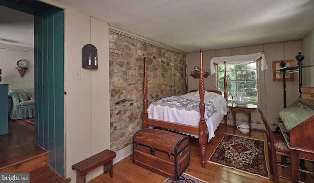 bedroom with wood finished floors and a baseboard heating unit