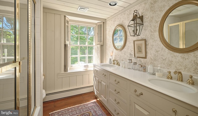 bathroom with baseboard heating, wallpapered walls, ornamental molding, a stall shower, and double vanity