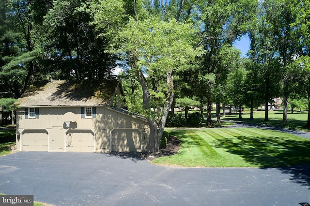 view of side of property featuring a garage and a lawn