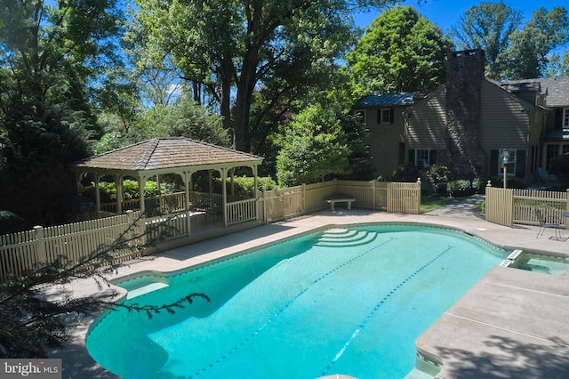 view of pool with a gazebo, fence, and a pool with connected hot tub