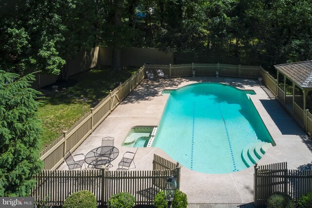 view of swimming pool featuring a fenced backyard, a patio, and a pool with connected hot tub