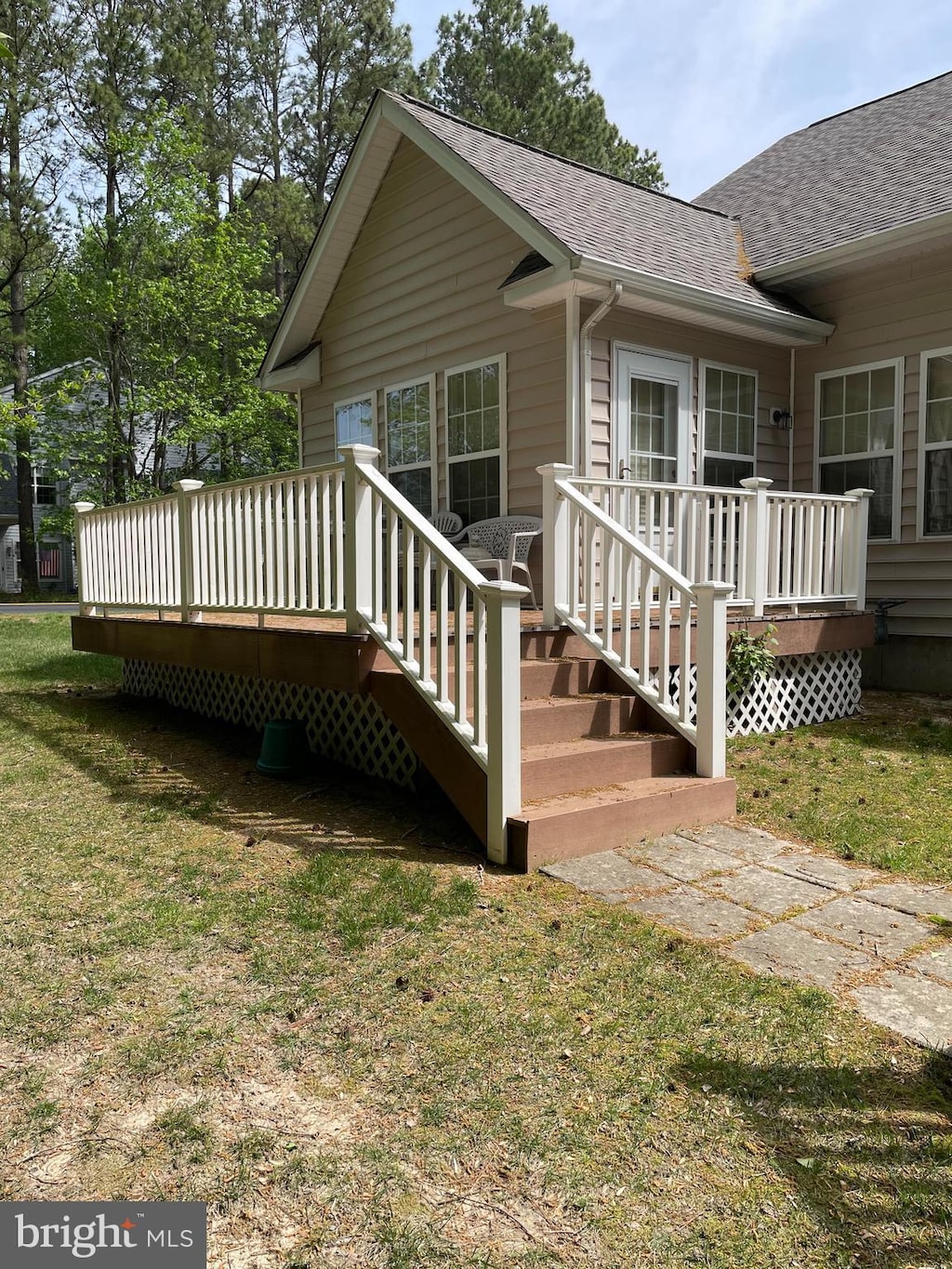 back of house with a lawn, a wooden deck, and a shingled roof
