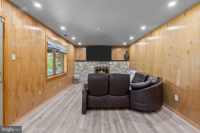 living room featuring light wood-style floors, wooden walls, a fireplace, and visible vents