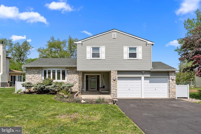 view of front of home with driveway, roof with shingles, a front yard, an attached garage, and stone siding