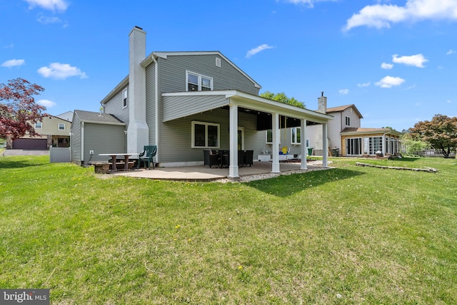 back of property with a patio, a yard, and a chimney