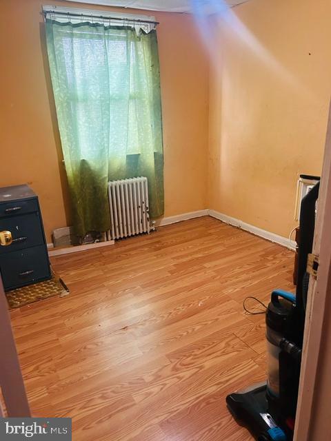 421 52nd St, Baltimore, MD 21224 - living room featuring radiator heating unit, wood finished floors, and baseboards