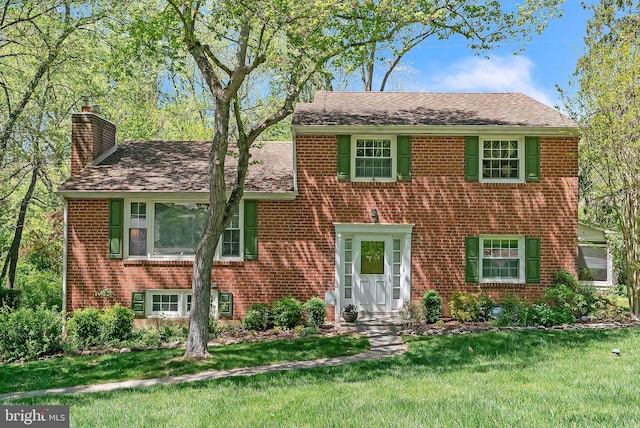 view of front of property with a chimney, brick siding, and a front yard