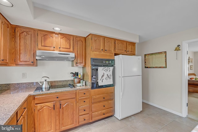 kitchen featuring brown cabinets, light tile patterned floors, baseboards, black appliances, and under cabinet range hood