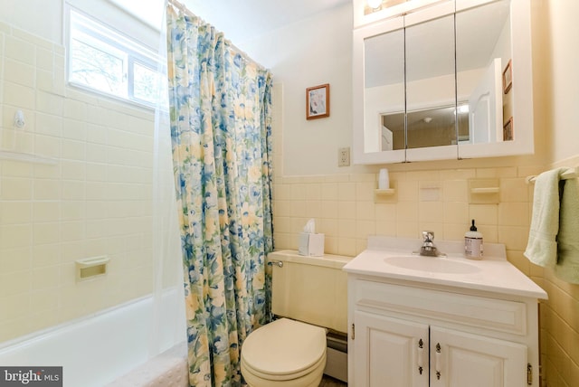 full bath featuring vanity, toilet, a wainscoted wall, tile walls, and shower / tub combo