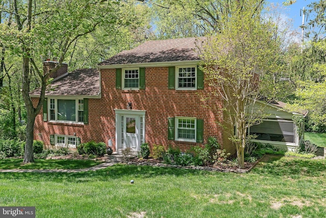 view of front facade featuring a chimney, brick siding, and a front yard