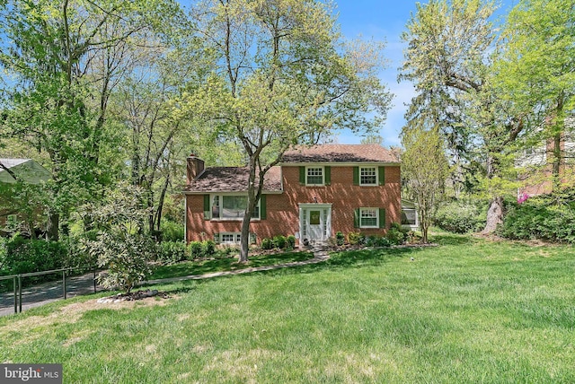view of front facade featuring fence, a chimney, a front yard, and brick siding