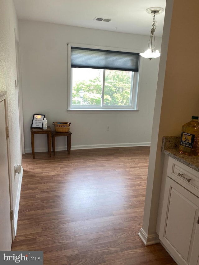 dining room featuring a chandelier, baseboards, visible vents, and wood finished floors