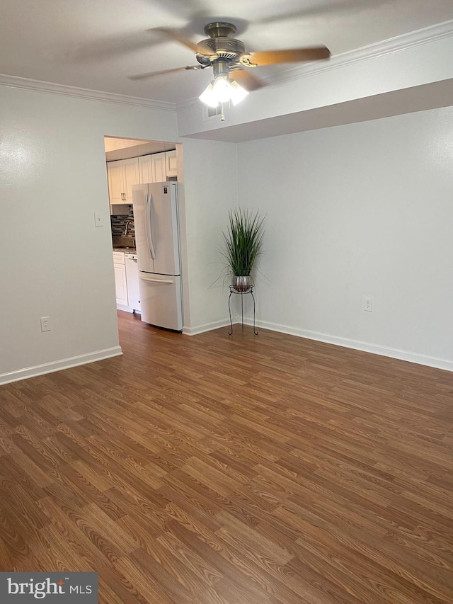 empty room with crown molding, a ceiling fan, baseboards, and dark wood-type flooring