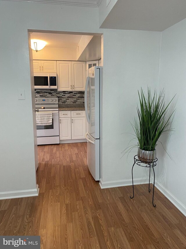 kitchen featuring dark countertops, white range with electric cooktop, wood finished floors, white cabinets, and freestanding refrigerator