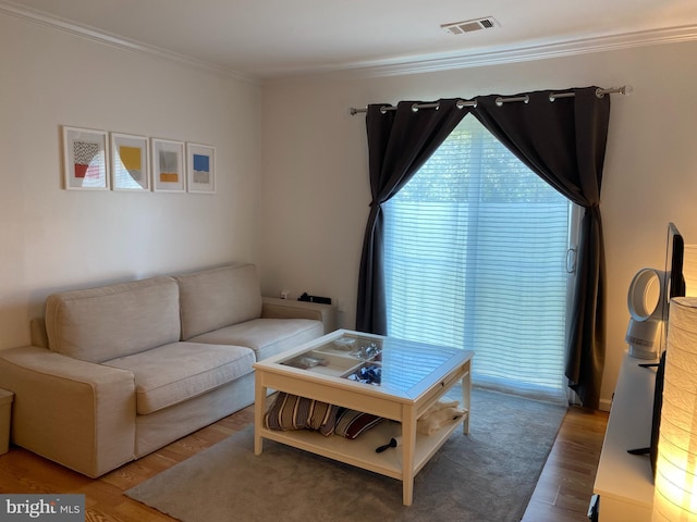 living area with visible vents, crown molding, and wood finished floors